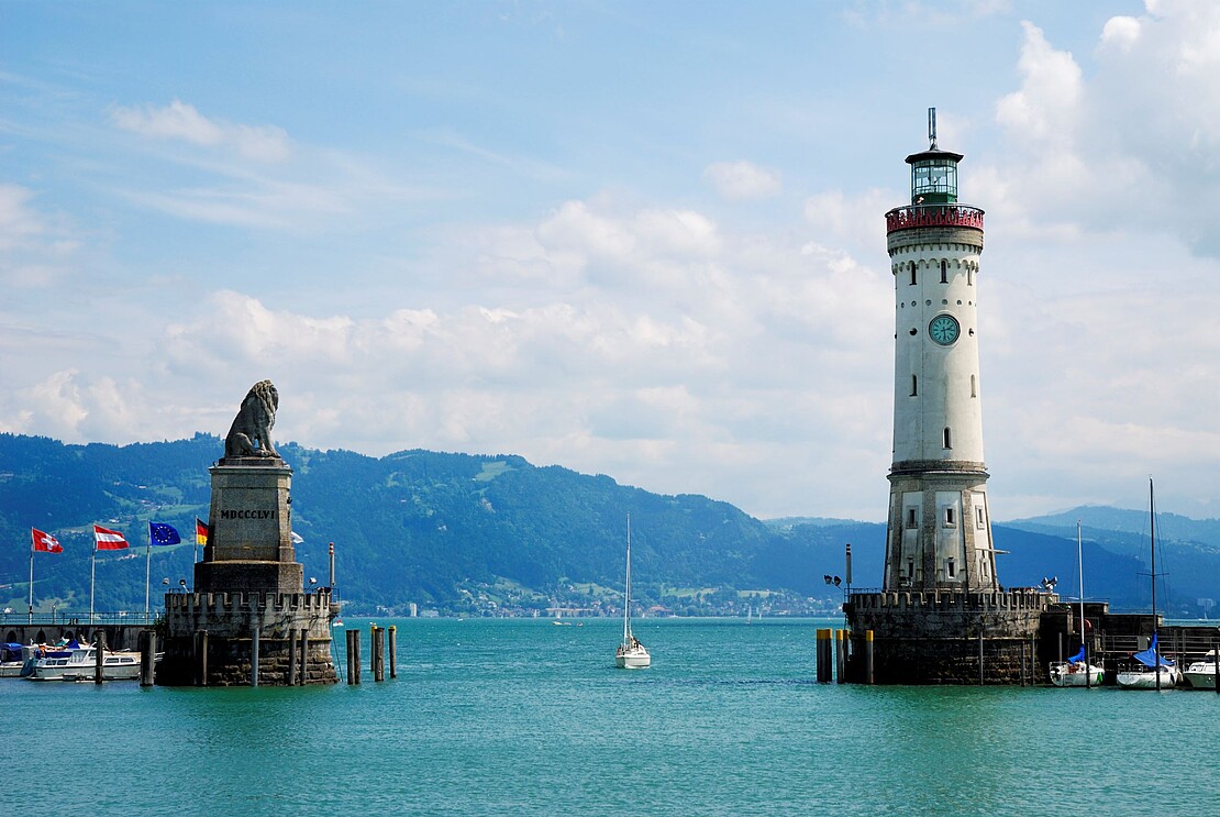 Hafen von Lindau mit Löwenstatue und Leuchtturm am Bodensee Der Hafen von Lindau mit der Löwenstatue und dem Leuchtturm, umgeben von der malerischen Kulisse des Bodensees.